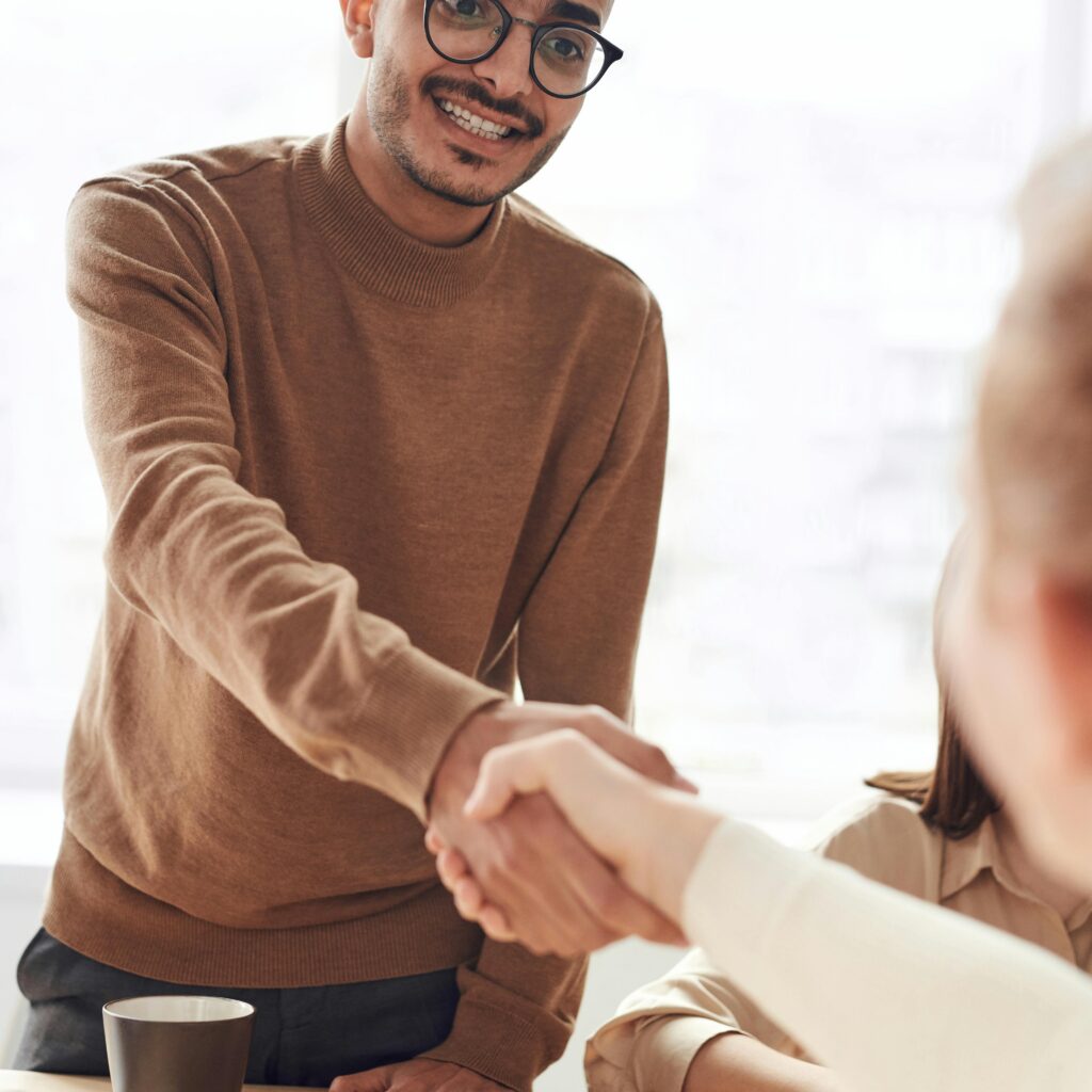 Smiling professionals engage in a welcoming handshake at a business meeting indoors.